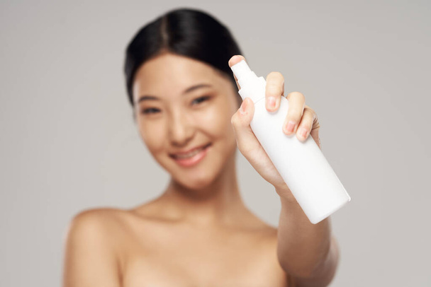 Portret van mooie aziatische vrouw met spray op geïsoleerde achtergrond  - Foto, afbeelding