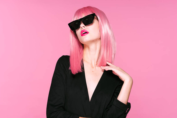 Young beautiful woman in pink wig and  black sunglasses on pink background - Foto, Imagen