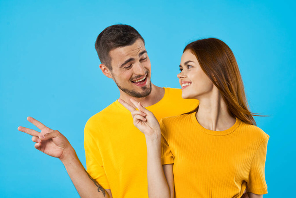 young  handsome man and woman showing something  in studio  on blue background  - Photo, Image