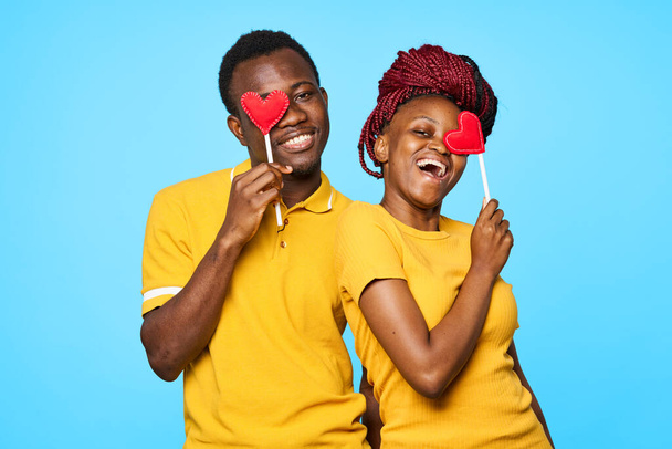 young beautiful couple with red hearts posing in studio on blue background - Valokuva, kuva