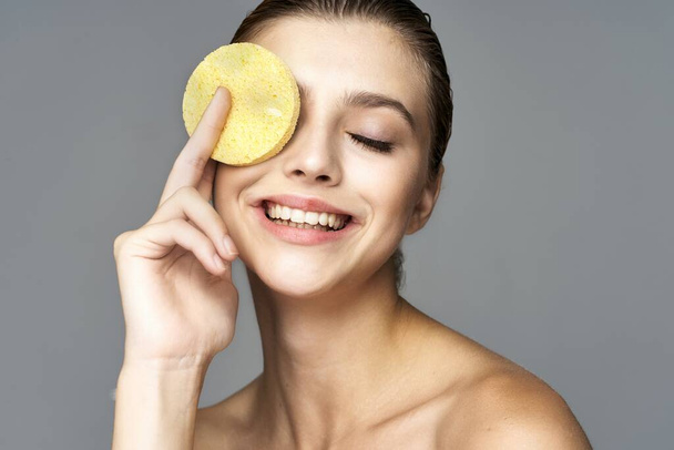 young beautiful woman holding sponge for cleaning skin  in studio  - Foto, Bild