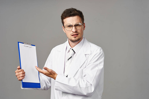 Studio shot. Young doctor  with clipboard on  isolated background  - Фото, изображение