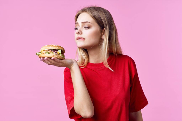 mujer sosteniendo hamburguesa en estudio - Foto, Imagen