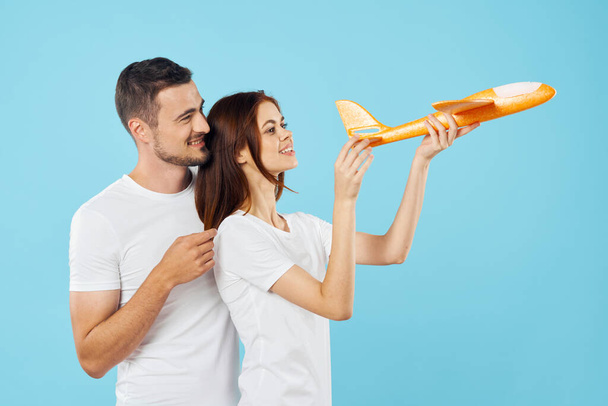 νεαρό ζευγάρι με αεροπλάνο παιχνίδι στο στούντιο, απομονωμένο φόντο    - Φωτογραφία, εικόνα