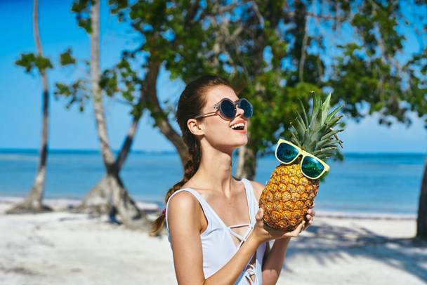 Een vrouw in een wit badpak met ananas. Hoge kwaliteit foto - Foto, afbeelding