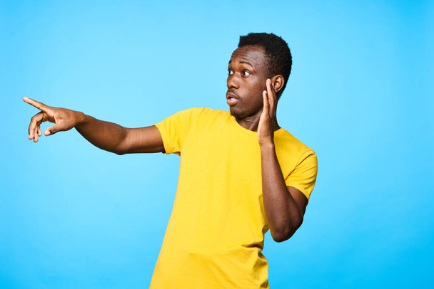 Joven africano señalando con el dedo aislado sobre fondo azul - Foto, Imagen