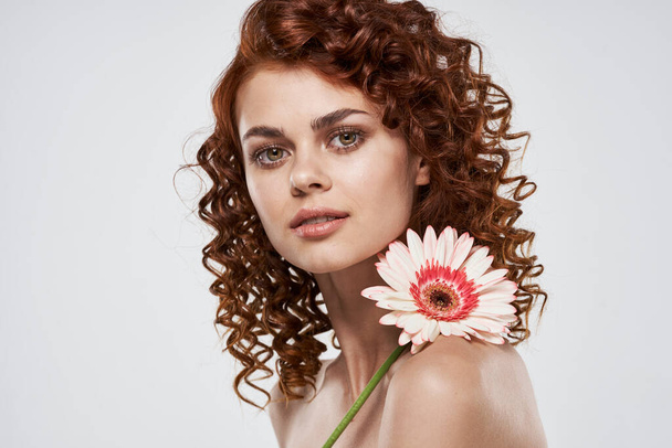 joven hermosa mujer con flor posando en estudio, aislado  - Foto, imagen
