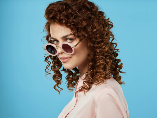 fiatal gyönyörű nő napszemüvegben pózol a stúdióban - Fotó, kép