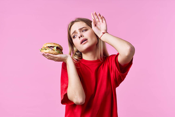 孤独を背景にハンバーガーを持つ美しい悲しい女性  - 写真・画像