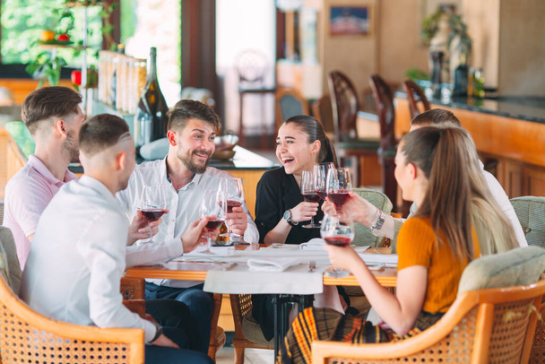 Friends drink wine on the terrace of the restaurant. - Фото, зображення