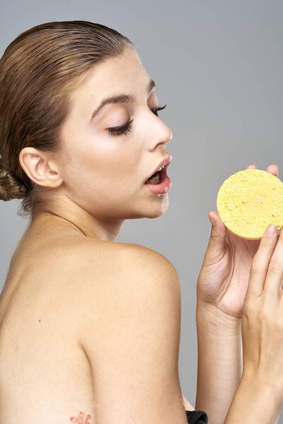young beautiful woman holding sponge for cleaning skin  in studio  - Photo, Image