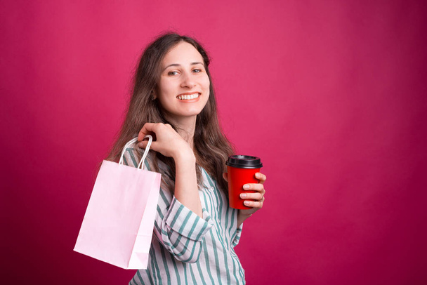 Joyful young lady is holding a to go cup and a shopping bag - Fotó, kép