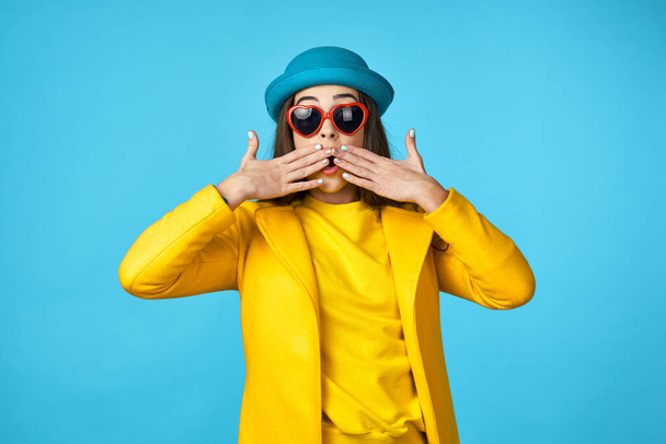 young beautiful woman in yellow jacket is surprised   in Studio with blue Background. - Φωτογραφία, εικόνα