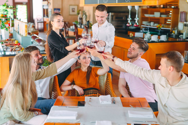 Friends drink wine on the terrace of the restaurant. - Fotoğraf, Görsel