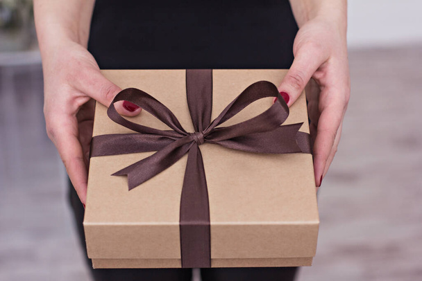 Le mani femminili tengono una scatola con un regalo. - Foto, immagini