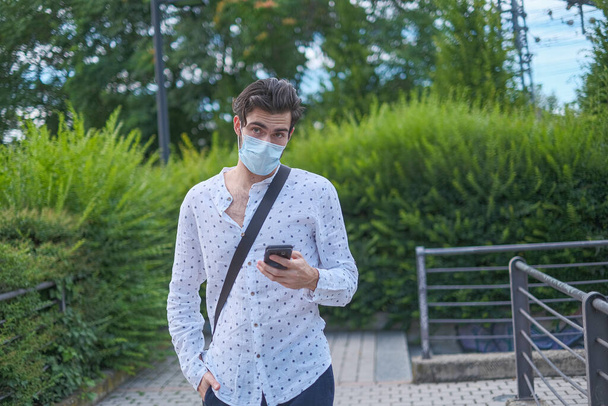 beau jeune homme se promenant autour de la ville avec masque chirurgical anti covid 19. Photo de haute qualité - Photo, image