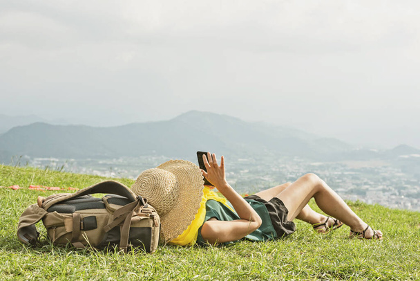 Asian woman lie on grassland and using cellphone - Photo, Image