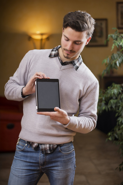 Beau jeune homme à la maison avec tablette PC dans ses mains - Photo, image