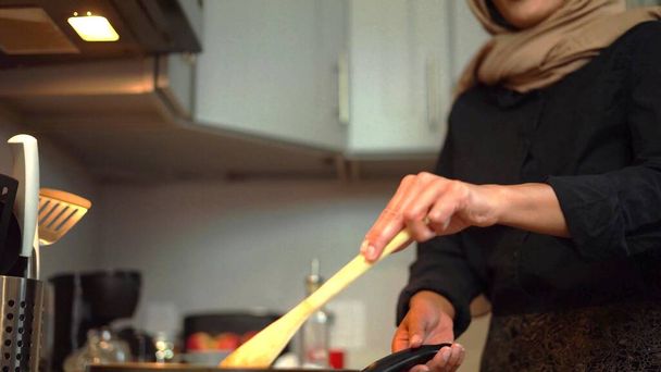 Foto einer verschleierten Frau, die in einer modernen Küche kocht - Foto, Bild