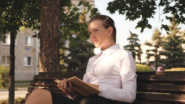 Gyönyörű, szabad nő, aki jó könyveket olvas. Női diák tanít az utcán egy könyvet a parkban egy padon. Egy fiatal lány portréja egy tankönyvvel a kezében. fiatal diák felkészülés vizsgákra - Fotó, kép