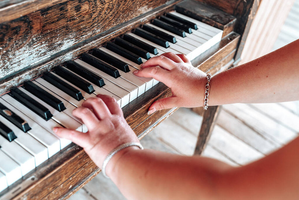 Femmina suona un vecchio pianoforte rustico, solo le braccia e le dita mostrate. Focus selettivo sulla mano destra - Foto, immagini