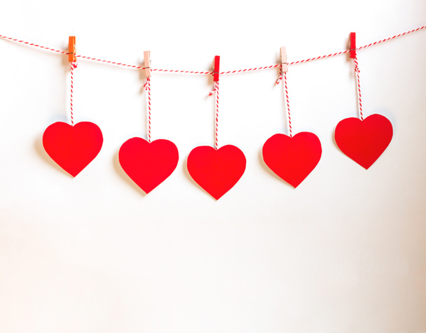 Κόκκινο χαρτί καρδιάς κομμένο με φυσικό κορδόνι και κόκκινα κλιπ που κρέμονται σε λευκό φόντο, αντίγραφο χώρου, ημέρα του Αγίου Βαλεντίνου - Εικόνα - Φωτογραφία, εικόνα