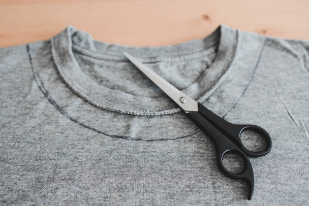 módní diy a upcycling staré oblečení koncept, tričko s nůžkami stříhat nový výstřih  - Fotografie, Obrázek
