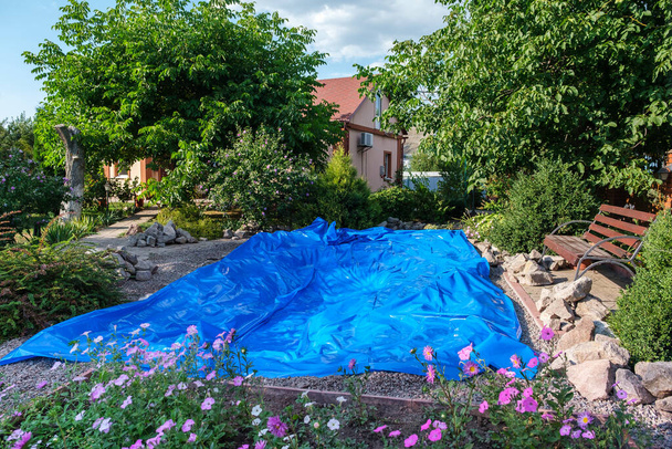 Выкатили голубой лист HDPE на землю, чтобы установить пруд для рыб - Фото, изображение