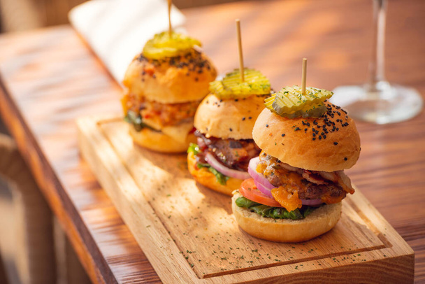 Small grilled burgers served to share on rustic table - Фото, зображення