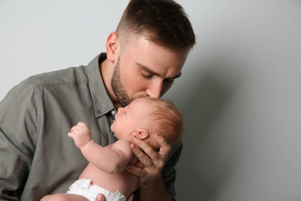 Father with his newborn son on light grey background - Foto, imagen