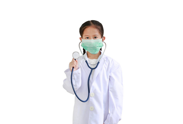 Portrait asian little kid girl showing stethoscope while wearing doctor's uniform and medical mask isolated on white background. - Fotoğraf, Görsel