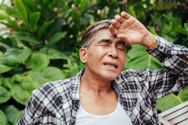 Egy idős ázsiai farmer portréja, aki belefáradt a szabadban való munkába egy farmon. - Fotó, kép