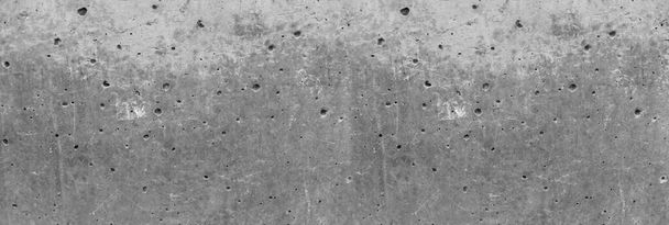 Tekstura starzejącej się i starzejącej się ściany zewnętrznej z szarego betonu. Mnóstwo dziur wokół powierzchni. Konstrukcja i materiały - Zdjęcie, obraz