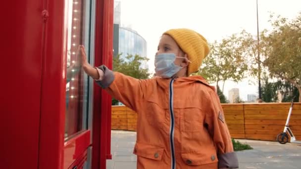 Dziecko w masce dotykając okna - Materiał filmowy, wideo