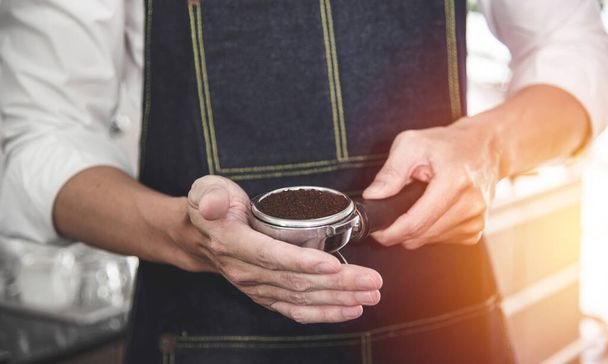 Barista drží nástavec, filtr na levobok a manipulátor s kávou. Výroba kávy espresso se připravuje na přípravu kávy pro zákazníky sloužit v oblíbených kaváren v Thajsku. - Fotografie, Obrázek