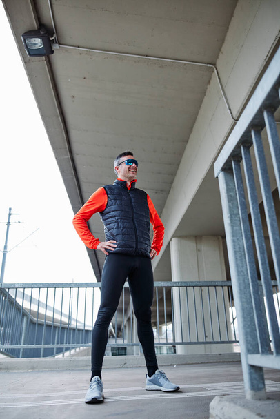 Middle aged attractive fit runner standing outdoors with hands on hips. - 写真・画像