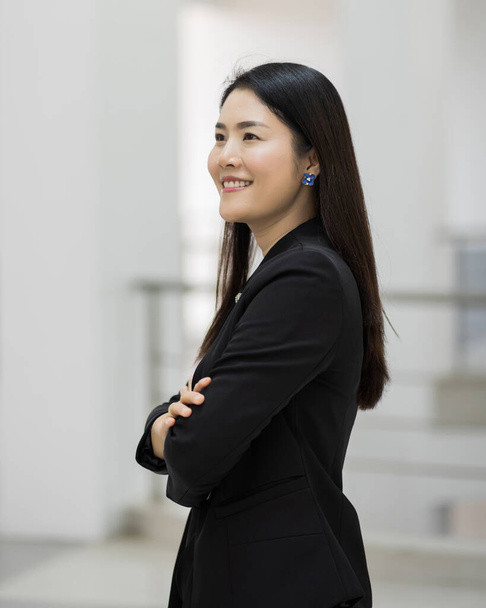 Portrait of a pretty middle age businesswoman standing Portrait of a cheerful middle-age businesswoman in business suit standing in the company building with confidence arms crossed. Modern business woman in the office with copy space. Business woman - Fotoğraf, Görsel