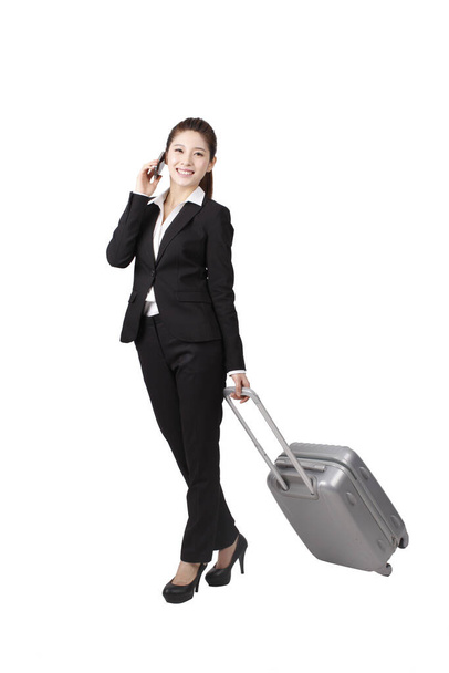 	Businesswoman using cell phone,pulling suitcase	 - 写真・画像