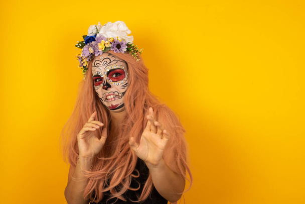 Mujer joven disgustada con máscara mexicana pintada tiene expresión facial insatisfecha como ve algo abominable o detestable - Foto, Imagen