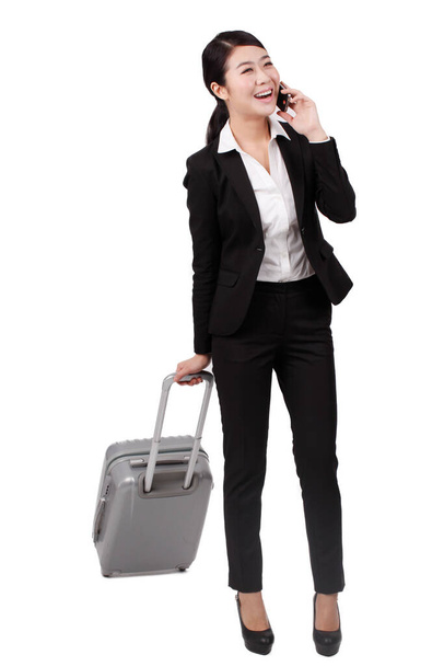 	Businesswoman using a cell phone,pulling a suitcase	 - Foto, imagen