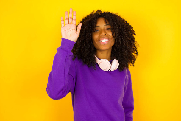 Afroamerikanerin hob ihre Hand auf gelbem Hintergrund. Emotionen und Gesten - Foto, Bild