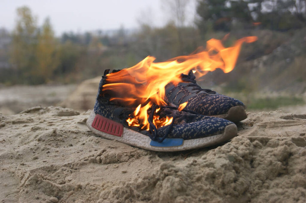 Used blue sneakers burning on a sand in the forest. Concept. Sport. Nobody comfortable shoes - Photo, Image