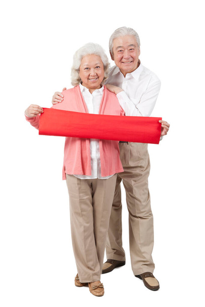 	Senior couple holding red streamer	 - Fotografie, Obrázek