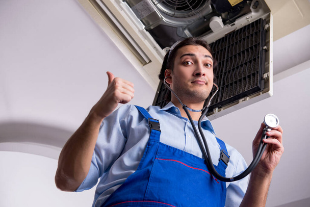 Jeune réparateur réparant unité de climatisation de plafond - Photo, image