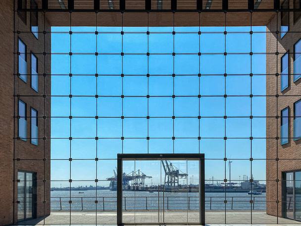 Business building in Hamburg with big windows and a view of the famous harbour and the container port through the windows - Valokuva, kuva