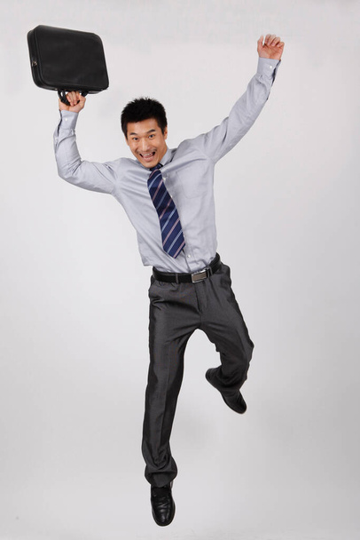 A young business man jumping with a briefcase - Photo, Image