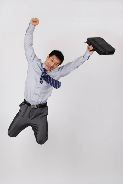 A young business man jumping with a briefcase - Фото, зображення