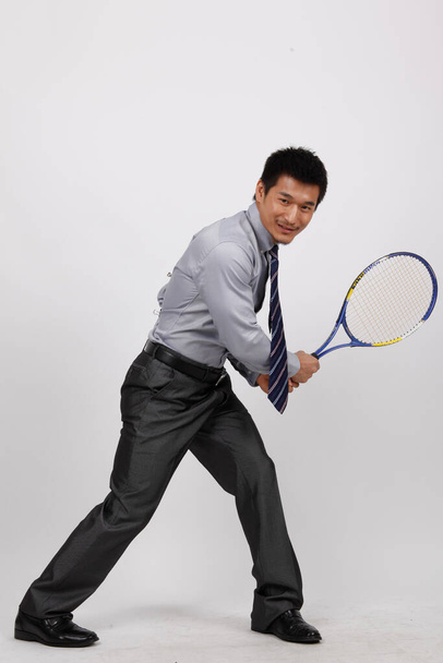 A young man playing badminton in business clothes - Foto, Bild