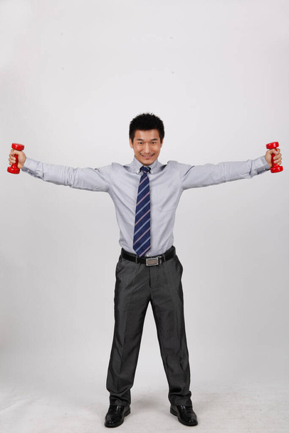 A business man with dumbbells - Foto, afbeelding