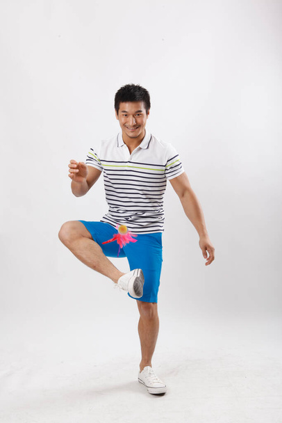 A young man in casual clothes kicking shuttlecock - Foto, Imagem